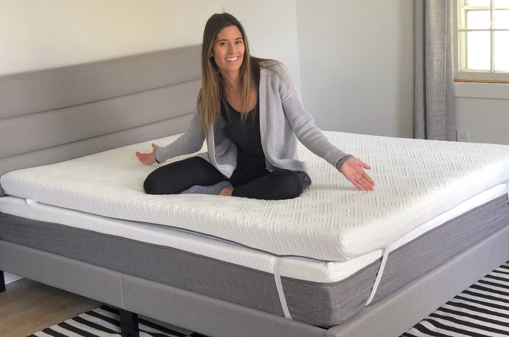 woman sitting on novilla mattress with hands out to the side