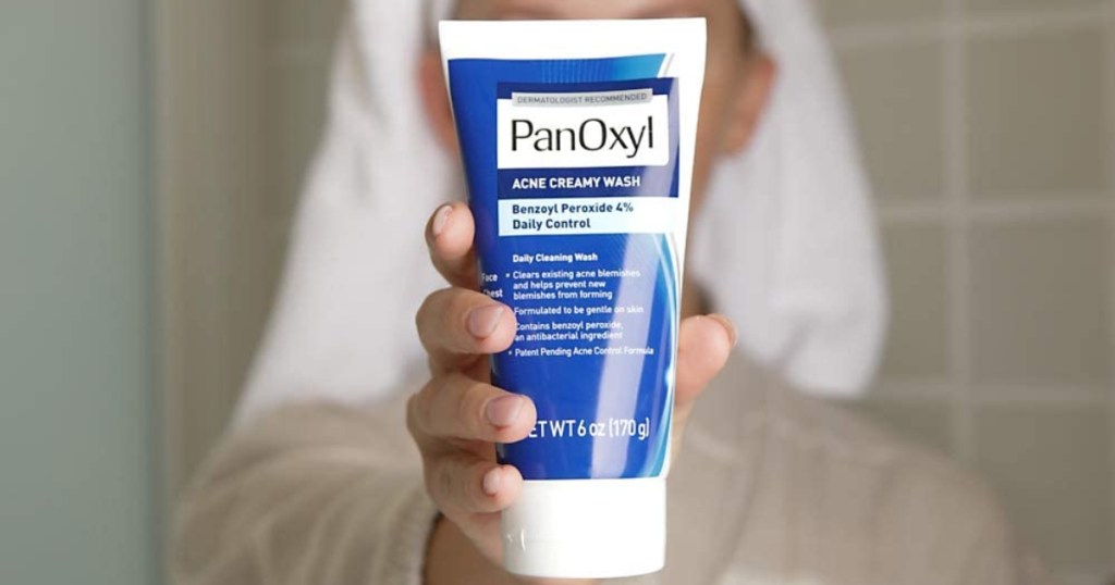 woman holding tube of PanOxyl in front of face