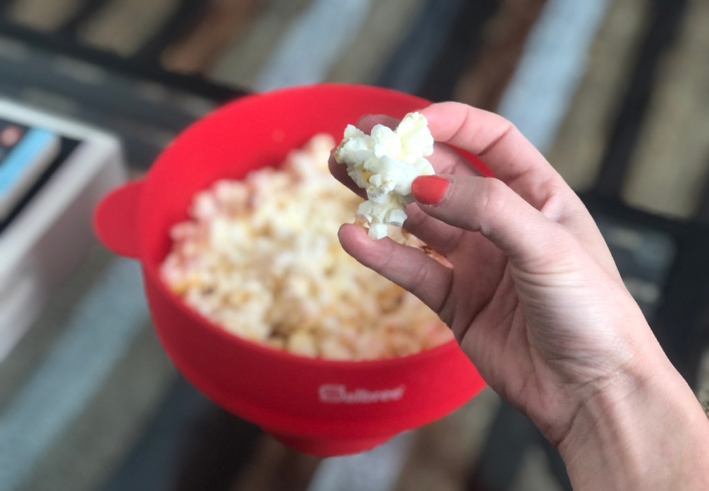 hand holding piece of popcorn overs silicone popcorn maker