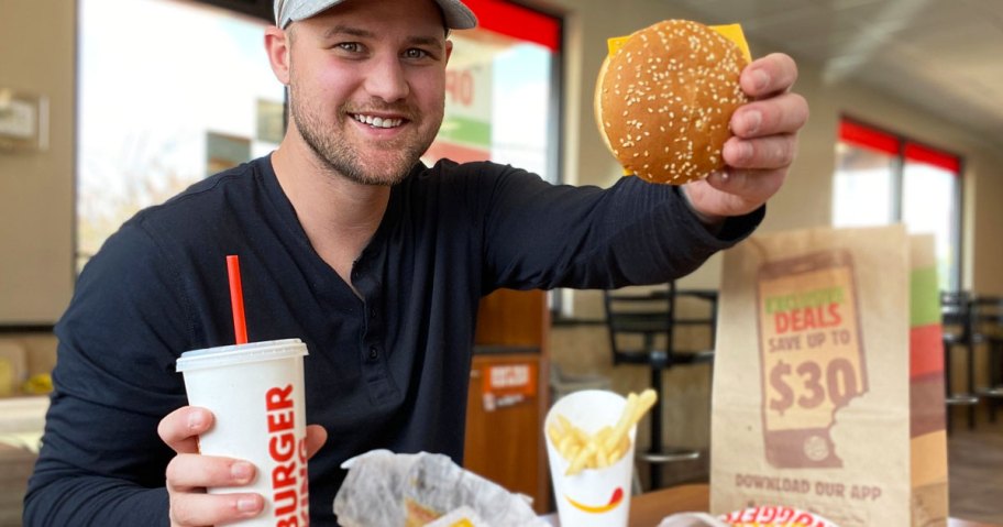 man holding up a burger king burger and drink