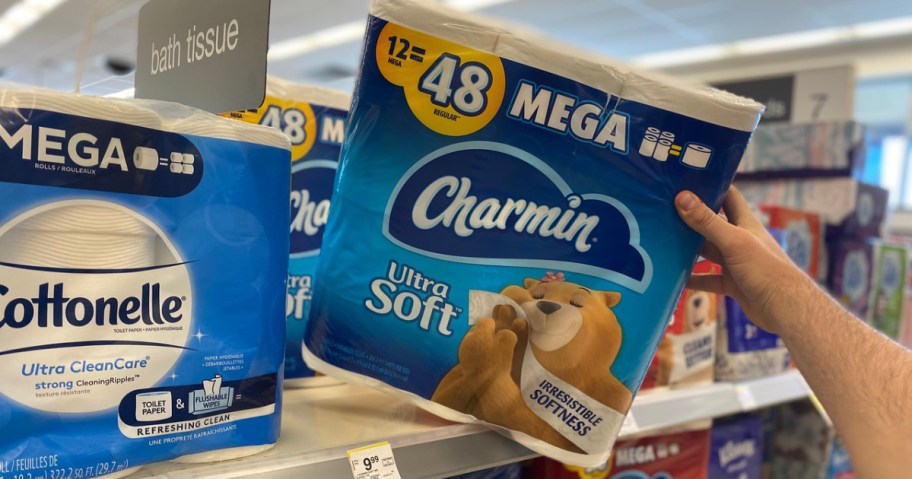 A hand grabbing a Charmin Mega Rolls 12 pack from a shelf