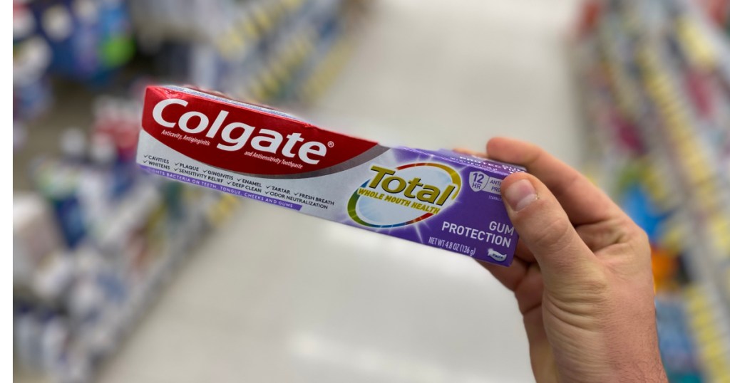 Hand holding white and purple box of toothpaste