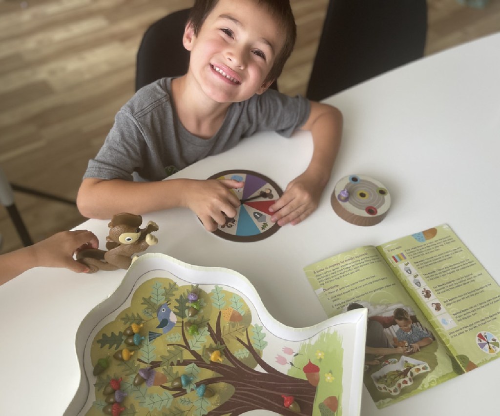 boy smiling and playing squirrel game at table