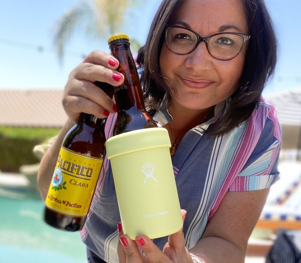 woman holding beer bottle in yellow cooler cup near pool