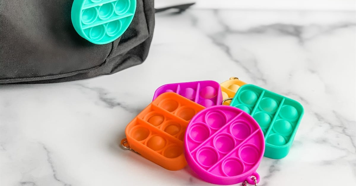 bubble pop keychains on a marble tabletop next to a black purse