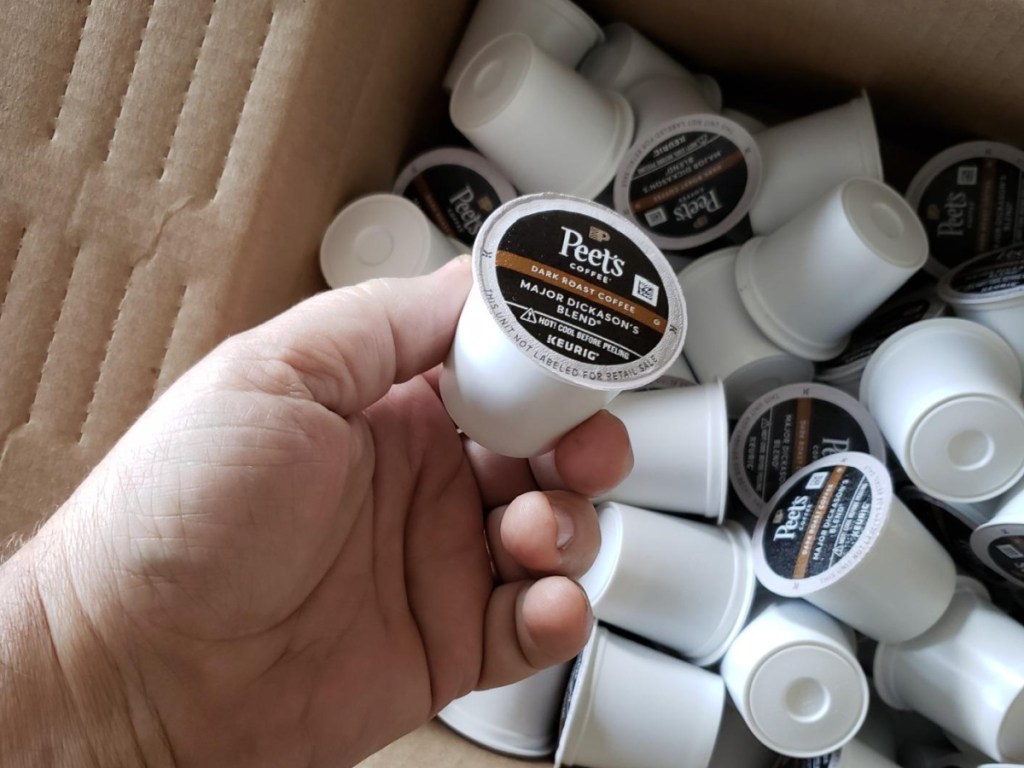 hand holding coffee pod and coffee pods in shipping box