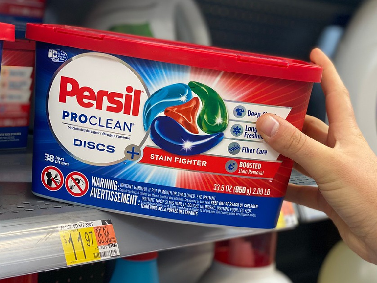 hand pulling a container of persil discs from a store shelf