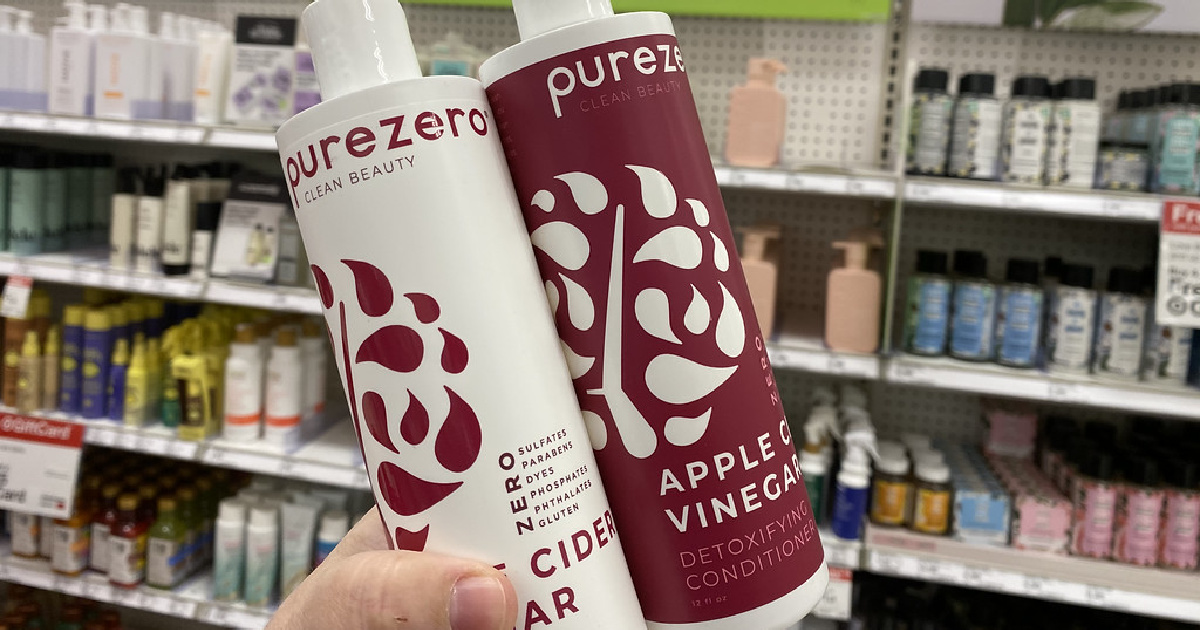 hand holding two bottles of purezero shampoo and conditioner in front of a target shelf