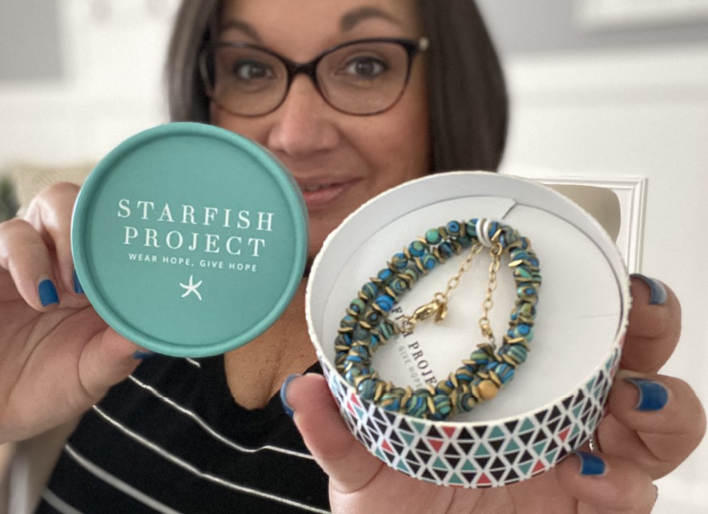 woman holding starfish project necklace