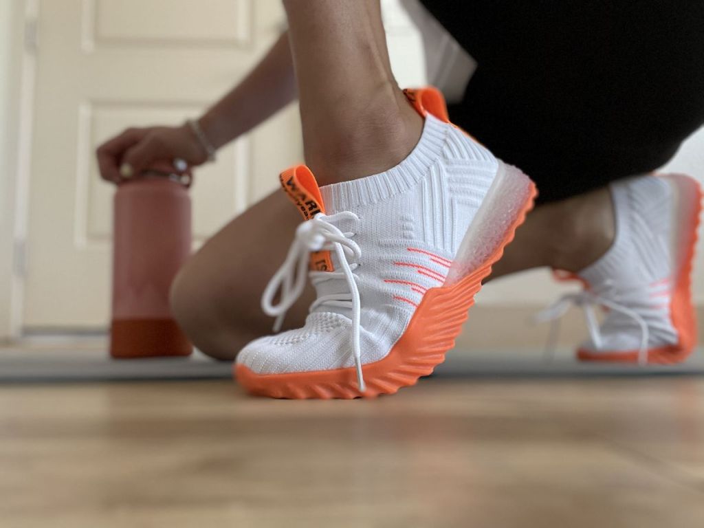 person wearing white and orange sneakers
