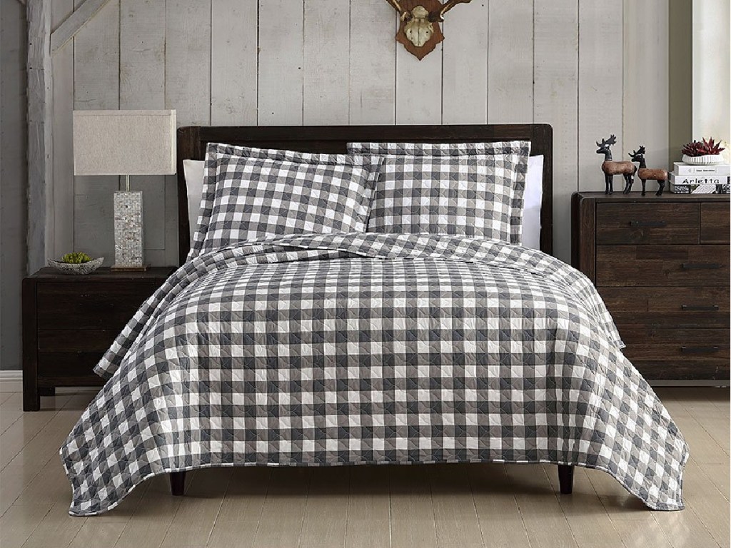 plaid quilt set on bed in bedroom with wood panel wall
