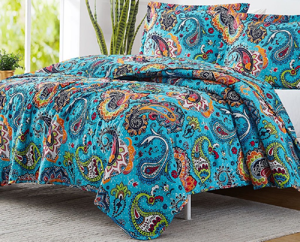 large teal paisley quilt set on bed