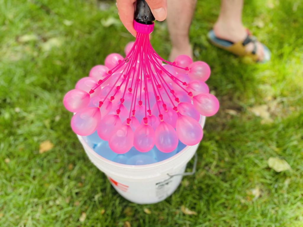 hand holding a water hose with water balloons on the end