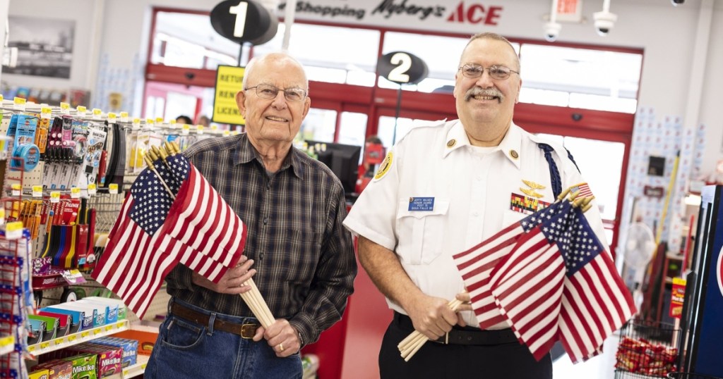 two men holding flags at Ace Hardware