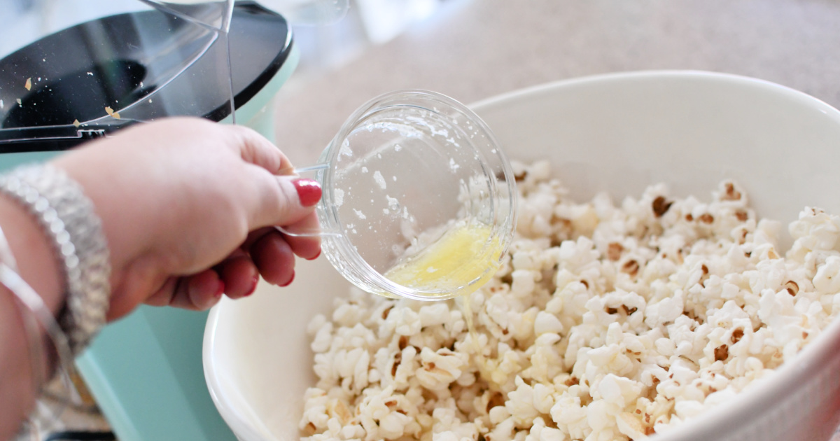 adding melted butter to popcorn