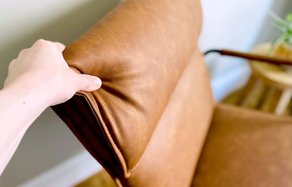hand pushing on back of brown modern leather chair