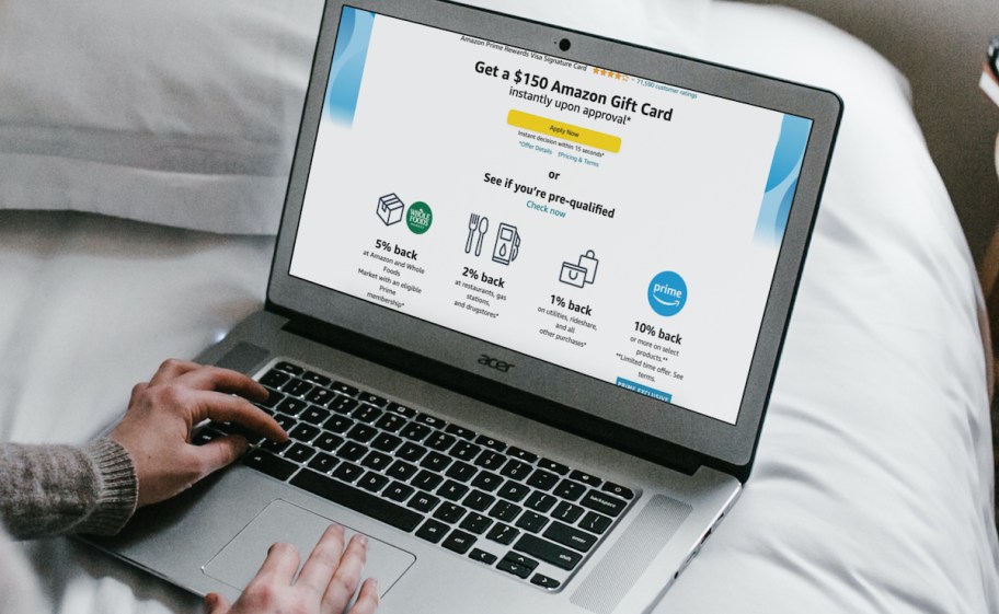 laptop sitting on bed with amazon credit card promotional deal on screen