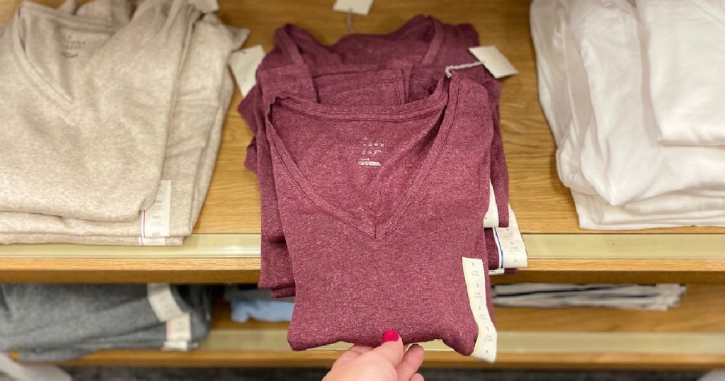 hand pulling out women's shirt on display at store