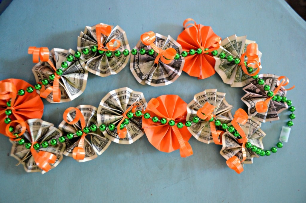 graduation lei with orange paper flowers and folded money