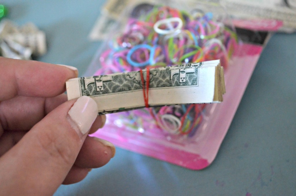 holding a folded dollar bill wrapped in a rubber band
