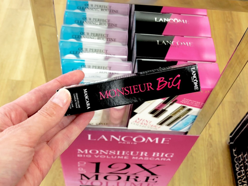 hand holding unopened pack of mascara by store display