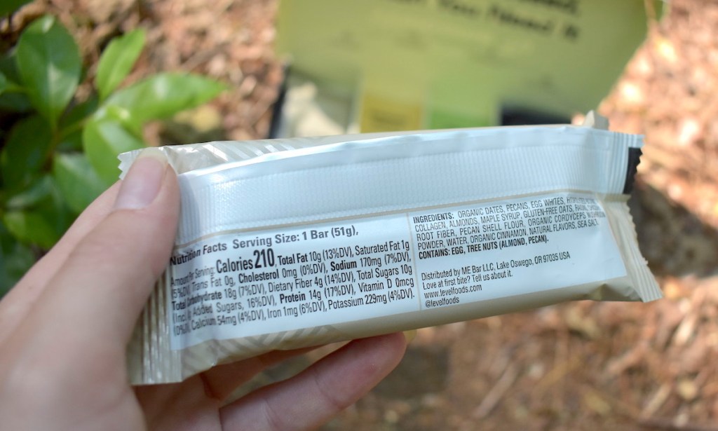 hand holding protein bar outside with close up of ingredients list