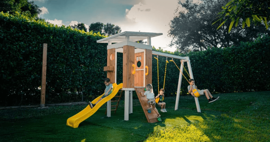 modern swing set with yellow slide outside in grass