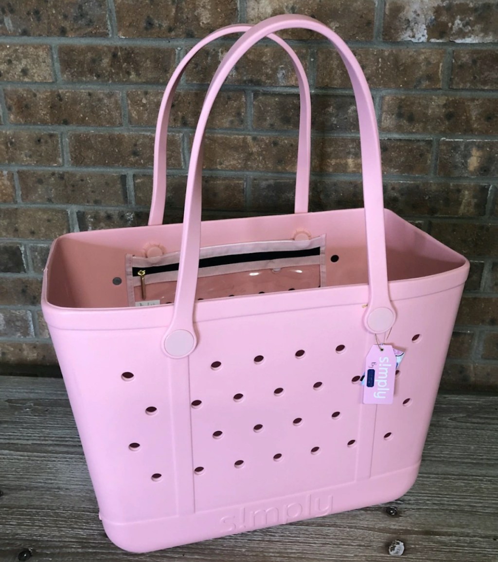 pink tote bag sitting in front of brick wall
