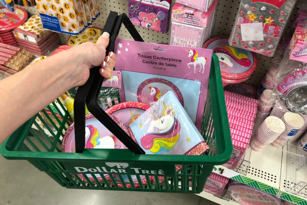 hand holding shopping basket with unicorn party supplies