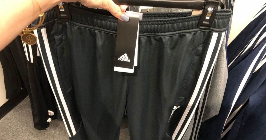 Woman wearing men's Adidas shorts and holding a hanger