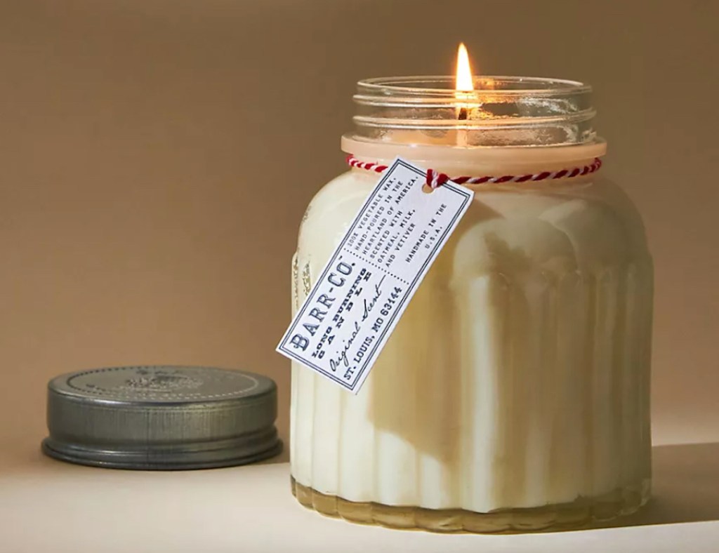glass jar candle burning with store brand tag and christmas string around top