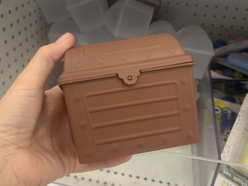 hand holding a small plastic treasure chest