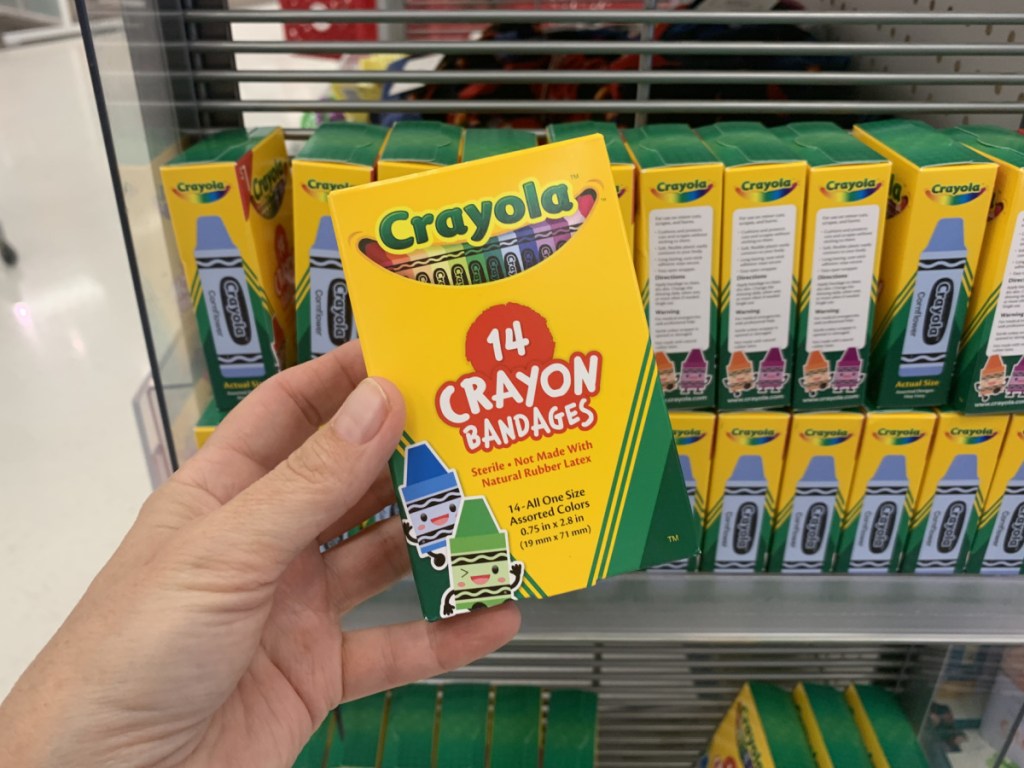 hand holding Crayola Crayon Bandages near in-store display