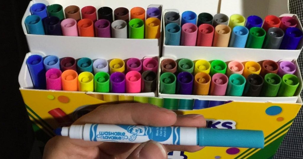 holding crayola marker nexxt to box of markers