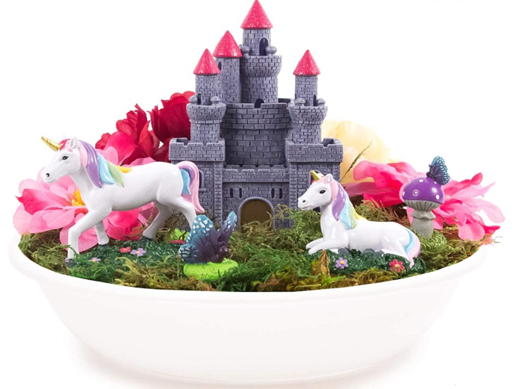 white planter filled with plants and castle and unicorn figurines