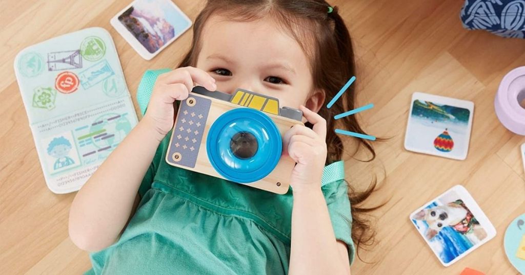 girl holding up wooden camera to her face