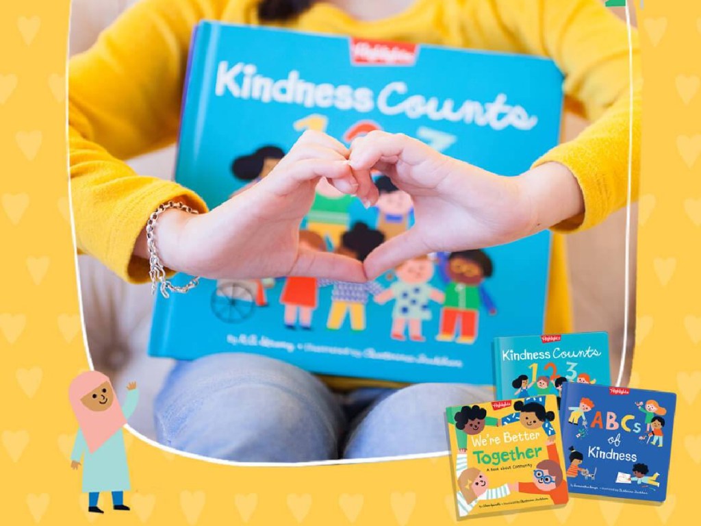 girl making heart sign with hands and holding kindness book on lap