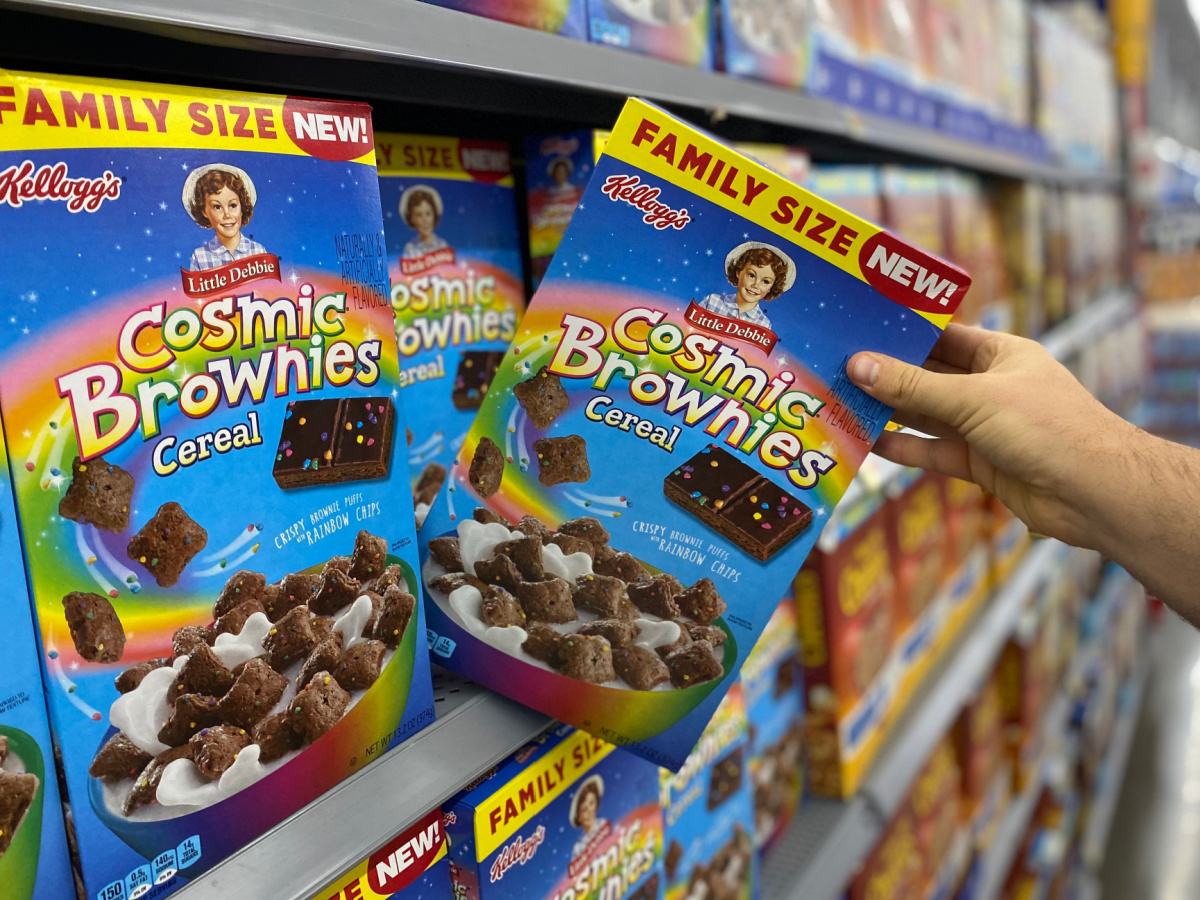 hand tipping a box of kellogg's little debbie cosmic brownies cereal off a store shelf