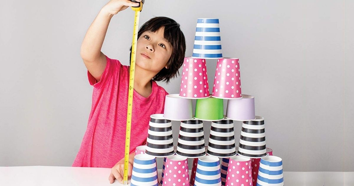 Boy measuring stacked paper cups with a measuring tape