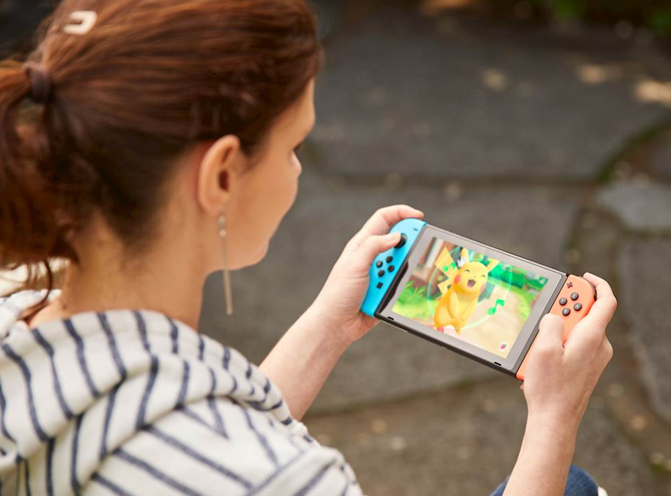 woman holding a Nintendo Switch and playing a pokemon game