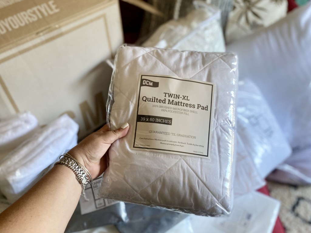 Person holding OCM Twin XL Mattress Pad in package
