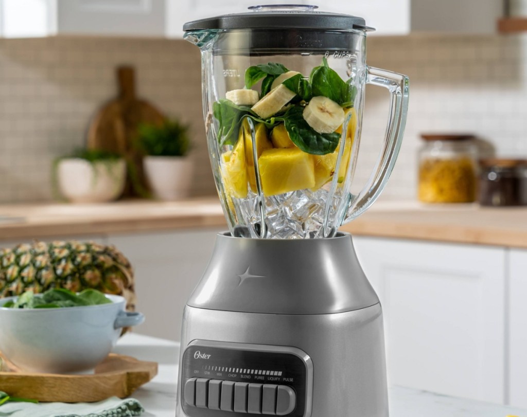 blender filled with ice, bananas and leafy greens