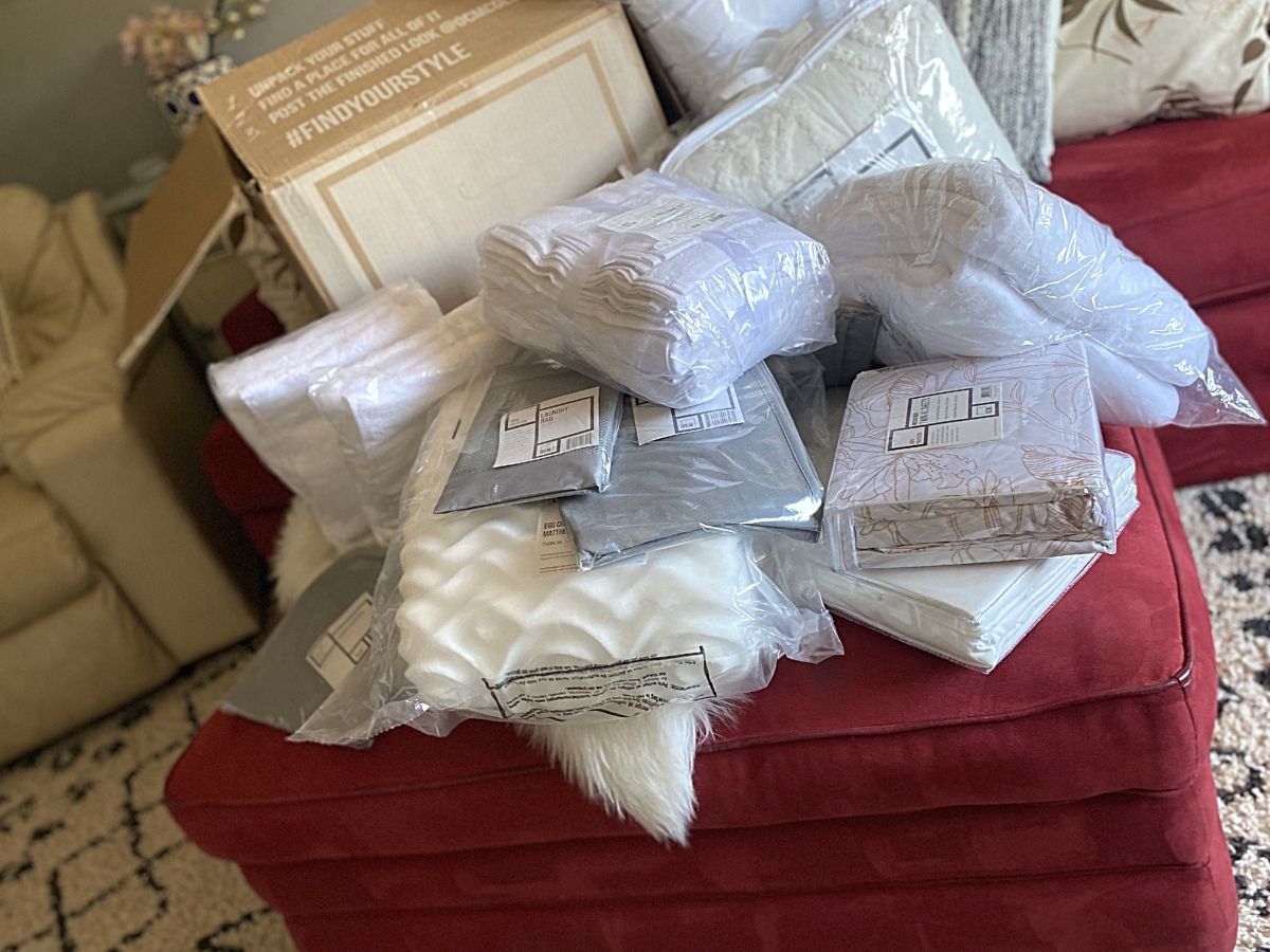 lots of bedding and bath items on red ottoman 