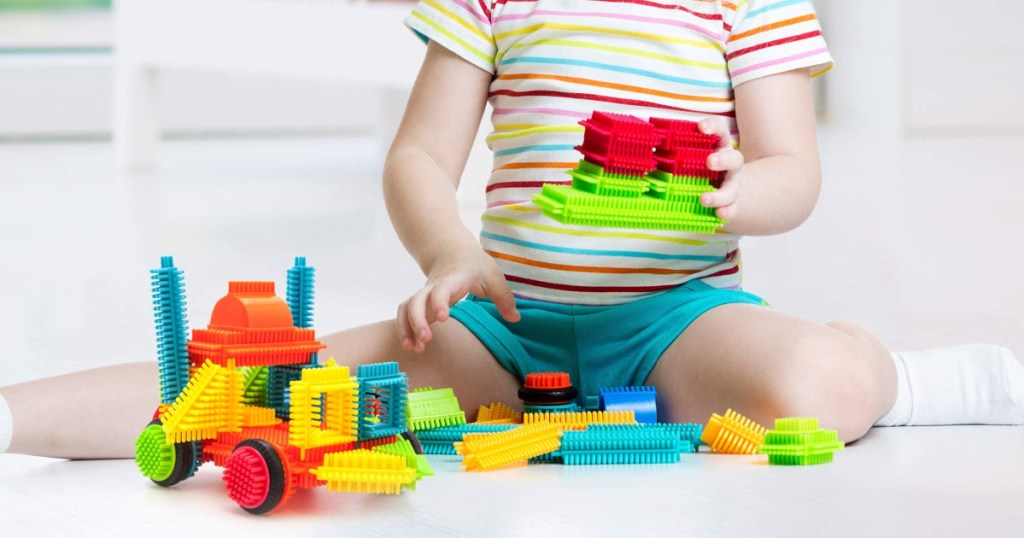 child sitting on the floor playing with bristle blocks
