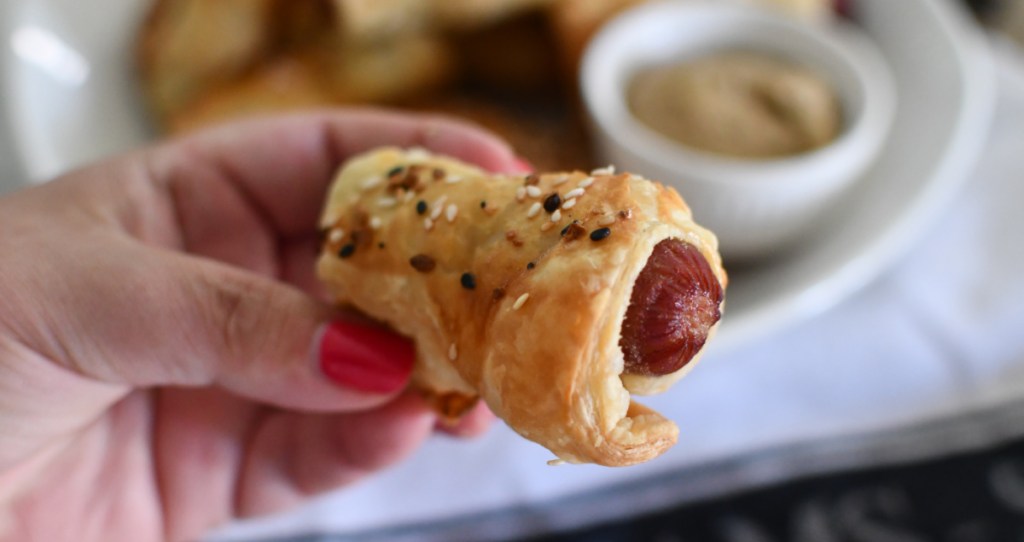 hand holding up a pigs in a blanket puff pastry snack