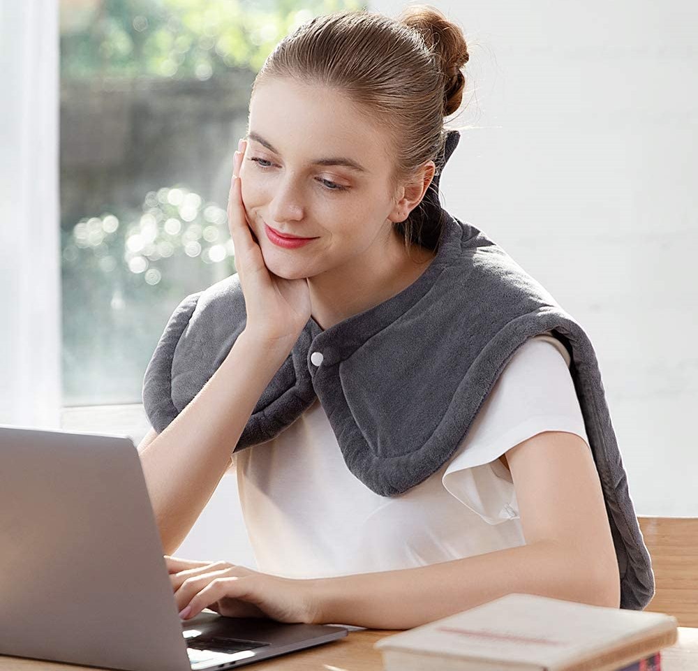 woman wearing a heating pad while looking at a computer