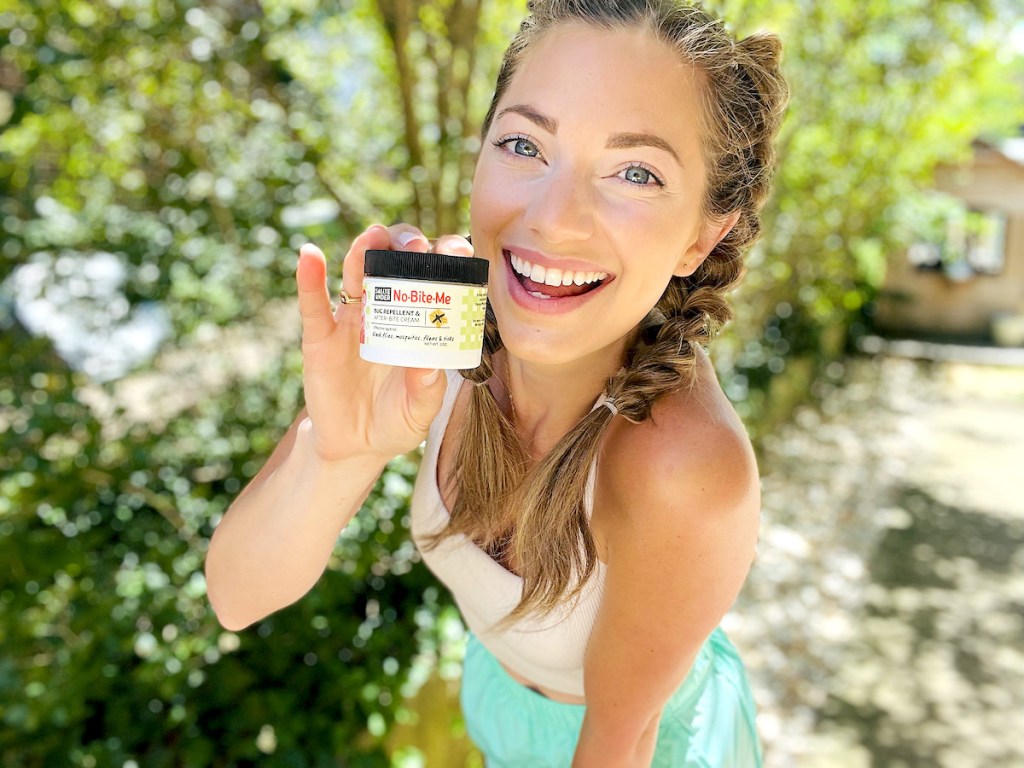 woman holding the best bug repellent smiling outside