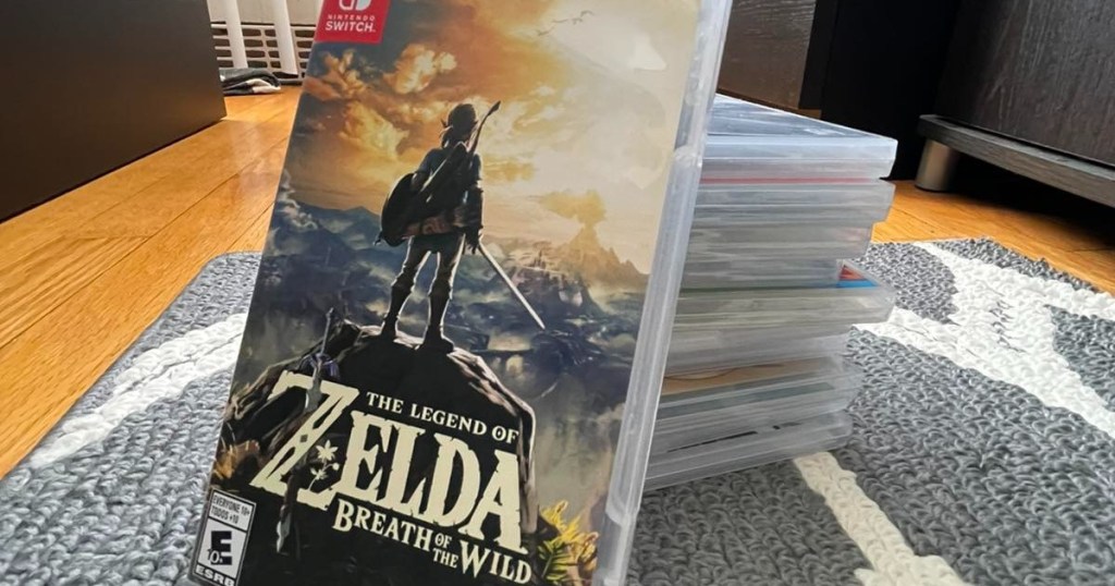 Legend of Zelda video game leaning against stack of video games on rug