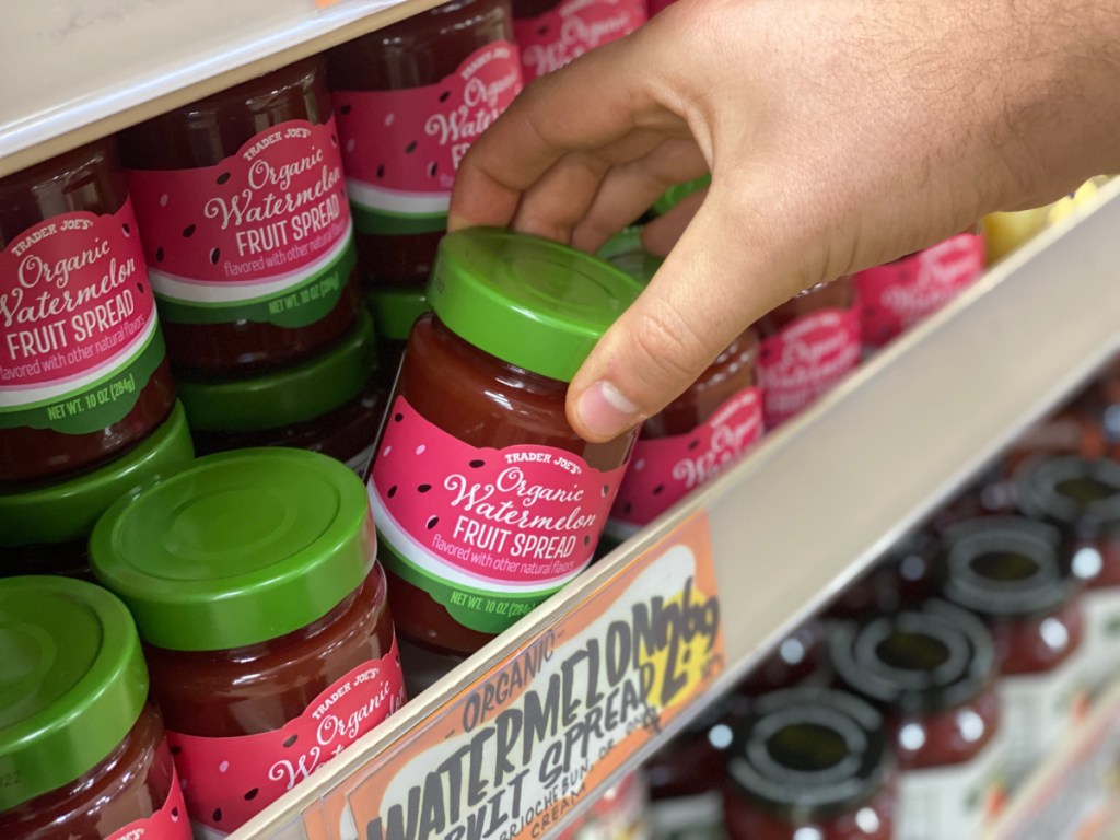 hand grabbing jar of jelly off store shelf