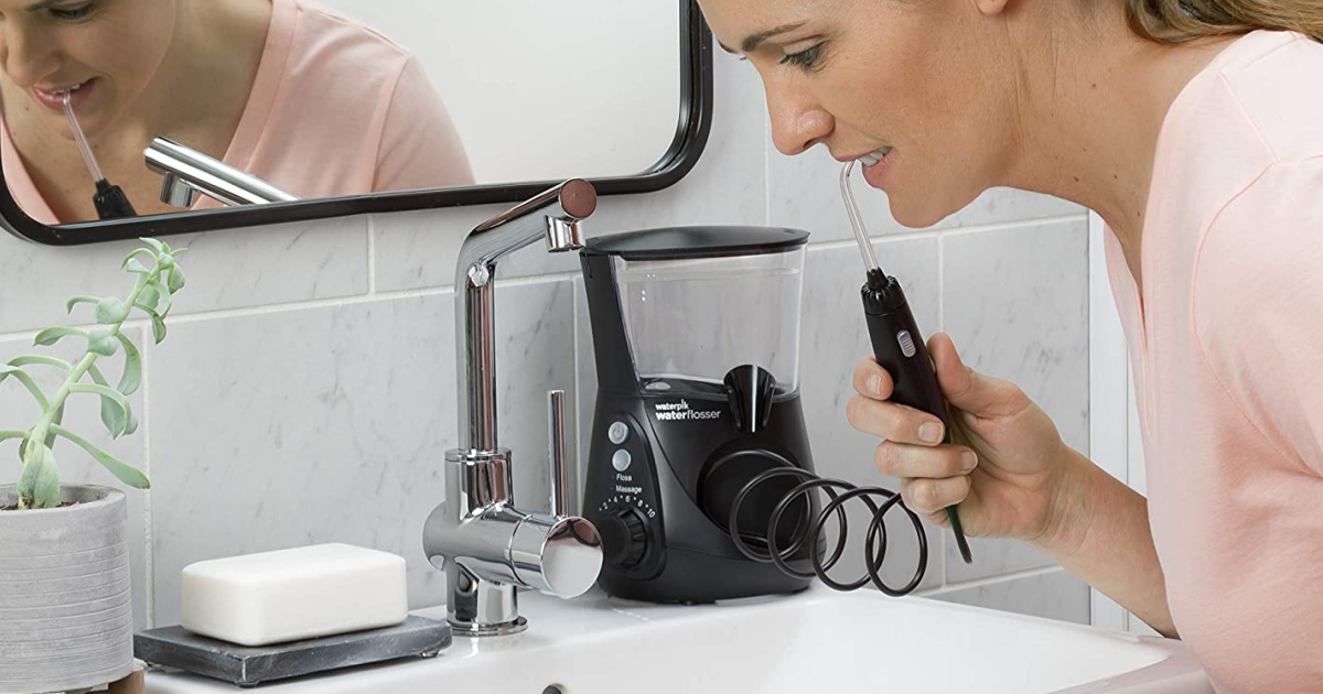 woman using black waterpik flosser in bathroom